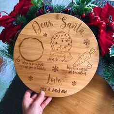 a person holding up a wooden plate that says dear santa