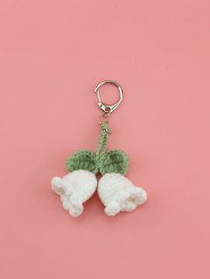 two crocheted cherries hanging from a keychain on a pink background