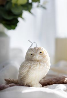 a white owl figurine sitting on top of a bed