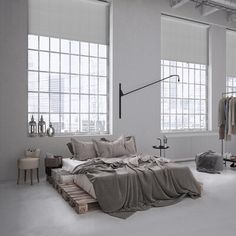 an image of a bed in the middle of a room with large windows and wooden pallets