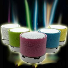 three different colored speakers sitting next to each other on top of a black background with colorful lights behind them