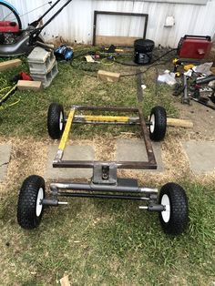 a cart made out of metal and wheels on the ground in front of a building