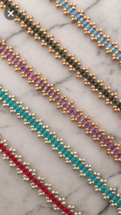 four different colored beaded bracelets on a marble surface with gold and silver beads