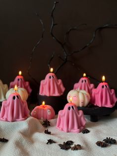 pink candles with ghost faces on them sitting in front of some spooky leaves