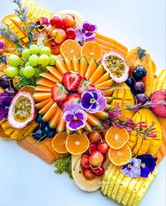 an arrangement of fruits and vegetables arranged on a platter with cornucons, grapes, oranges, kiwis, strawberries