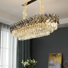 a chandelier hanging from the ceiling in a living room with grey walls and curtains