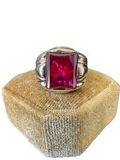 Handsome vintage 10k yellow gold 1940s era ring featuring a vibrant created ruby! The deep red gem weighs an estimated 6 carats, is emerald cut, and securely bezel set. The substantial setting is detailed with a decorative design on the shoulders. Charming vintage piece of fine jewelry for him or her, featuring July's birthstone! ERA - Circa 1940 METAL / MATERIAL - 10k yellow gold, 1 created ruby (estimated 6 carats) [Synthetic ruby contains essentially the same chemical composition & properties as its natural counterpart, but is created by man in controlled setting.] HALLMARKS / HISTORY - 10k SIZE / MEASUREMENTS - Size: 10, Created Ruby: Approx. 12 x 10 mm, Back of shank: 4.5 mm, Ring Head Height: 16 mm, Weight: 6.9 grams Jewelry For Him, Rubin Ring, Ruby Ring Vintage, Retro Era, Decorative Design, July Birthstone, Ruby Ring, Metal Material, Ring Vintage