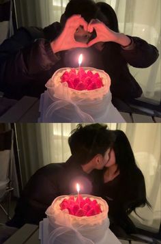 a man and woman sitting in front of a cake with candles on it, making the shape of a heart