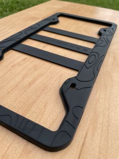 a close up of a wooden table with black metal brackets on the side and grass in the background