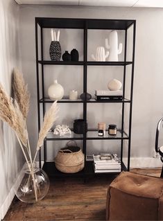 a shelf with vases, books and other items on it in a living room