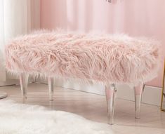 a pink bench sitting on top of a wooden floor next to a mirror and rug