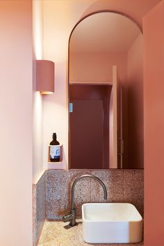 a bathroom sink sitting under a mirror next to a wall mounted faucet and light