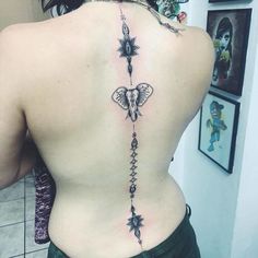 the back of a woman's body with an elephant and stars tattoo on it