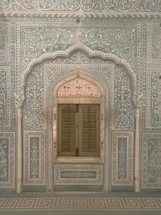 an intricately painted wall with wooden shutters and window in the center, surrounded by ornate carvings