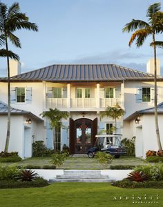 a golf cart parked in front of a large white house with palm trees around it