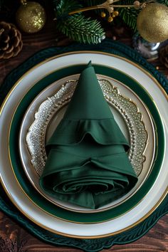 a place setting with green napkins and gold rimmed plates, pine tree decorations