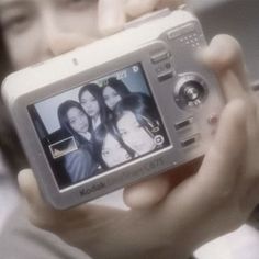 a man holding up a camera to take a picture with two women on it's screen