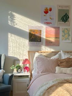 a bed sitting in a bedroom next to a chair and window with pictures on the wall