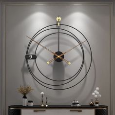 a large clock mounted to the side of a wall next to a table with vases on it