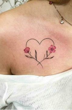 a woman with a heart shaped tattoo on her chest and flowers in the middle of it