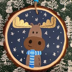 a wooden ornament with a moose wearing a scarf on it's neck