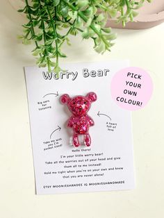 a pink bear brooch sitting on top of a card