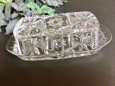 a clear glass dish sitting on top of a table next to a green leafy plant