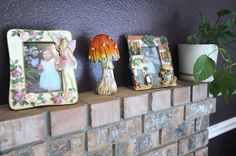 there are three pictures on top of the brick fireplace mantel, one with an angel and another with a flower