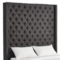 an upholstered headboard with two white pillows on the bottom and one side