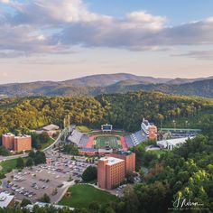 an aerial view of a college campus surrounded by trees and mountains in the distance,