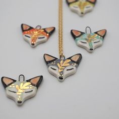 five necklaces with different designs on them sitting next to each other and one has a fox's head painted on it