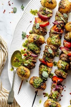 a white plate topped with skewered meat covered in pesto and tomato sauce