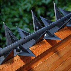 several metal spikes on top of a wooden fence