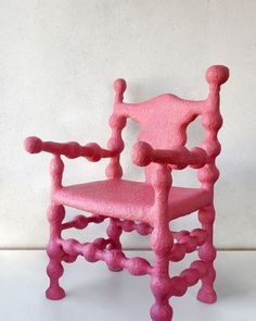 a pink chair sitting on top of a white floor