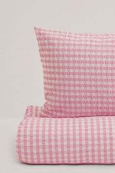 two pink and white striped pillows sitting next to each other