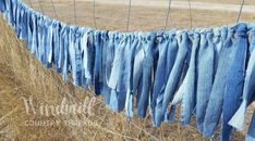 some blue jeans hanging on a wire in the middle of a dry grass field,