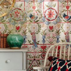 a white chair sitting in front of a wall covered with flowers and hearts on it