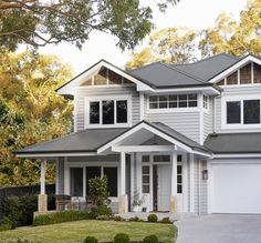 a white house with grey roofing and two car garages in front of it