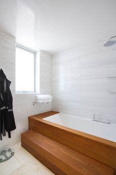 a bathroom with a large bathtub next to a window and towel rack on the wall