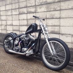 a black motorcycle parked next to a brick wall