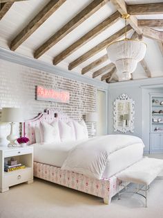 a white bed sitting in a bedroom next to a brick wall and wooden beams