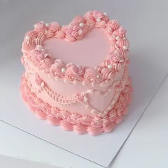 a pink heart shaped cake on top of a white table