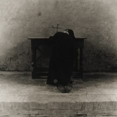 a person kneeling down in front of a bench with a cross on it's back