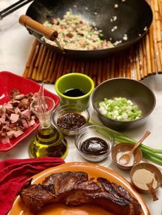 an assortment of food on a table including meat, sauces and seasoning bottles