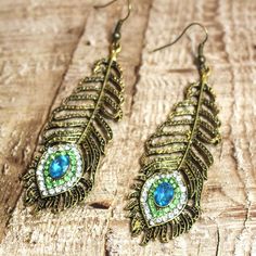 a pair of gold tone earrings with blue and green stones in the shape of a peacock's feather