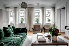 a living room with green couches and white curtains on the window sill,