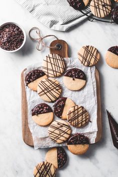 cookies with chocolate drizzled on them sitting on top of a cutting board