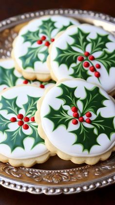 christmas cookies decorated with holly and red berries on a silver platter, ready to be eaten