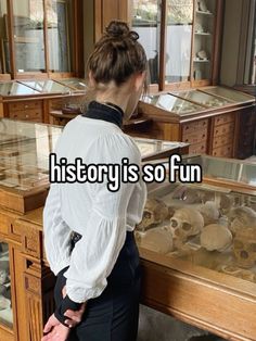 a woman standing in front of a display case filled with human skulls and bones that reads history is so fun