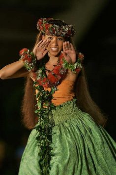 a woman in a green and orange dress with flowers on her head